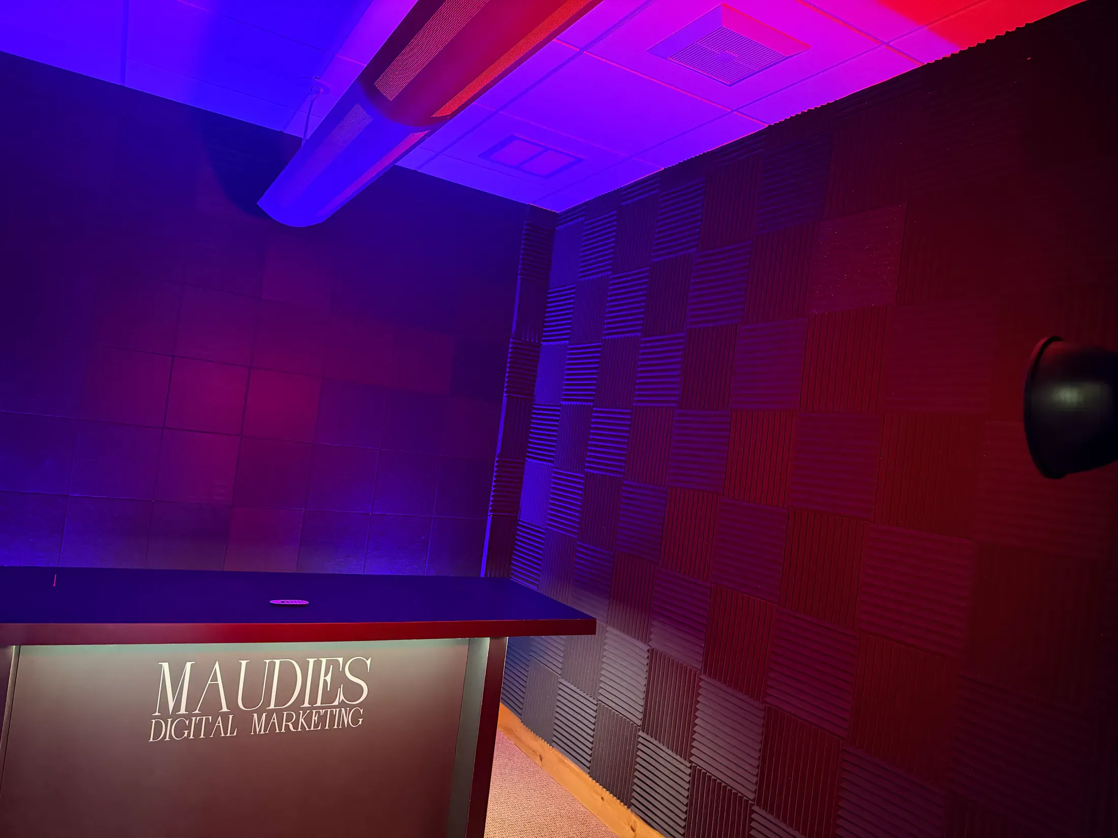 The Maudie’s podcast studio with acoustic wall treatment and purple and red lighting